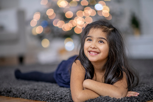 A sweet little Asian girl poses in her Christmas dress for a portrait