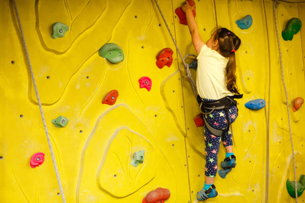 little girl climbing a rock wall indoor little girl climbing a rock wall indoor indoor playground stock pictures, royalty-free photos & images