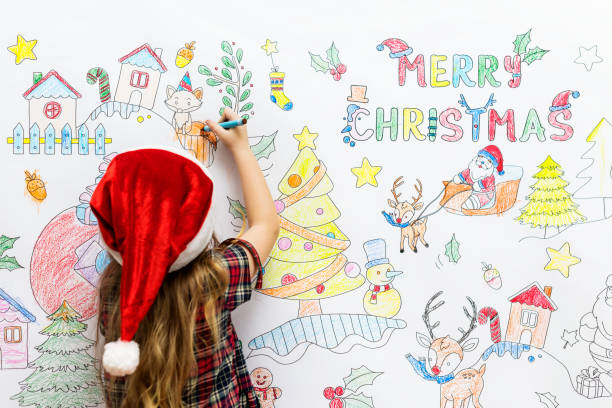Little girl drawing Christmas pictures on a white wall Little girl drawing Christmas pictures on a white wall christmas coloring stock pictures, royalty-free photos & images