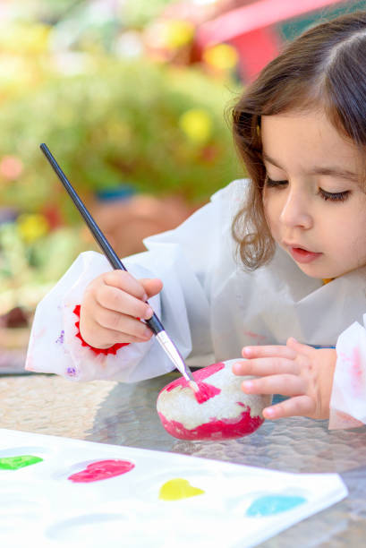 Little Girl Drawing On Stone Outdoors In Summer Sunny Day. Portrait of little child painting, summer outdoor.Kid drawing on a stone. cute arab girls stock pictures, royalty-free photos & images