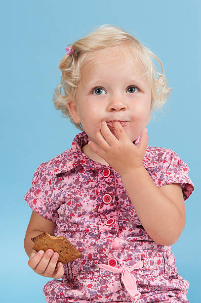 Little girl eating a biscuit. stock photo