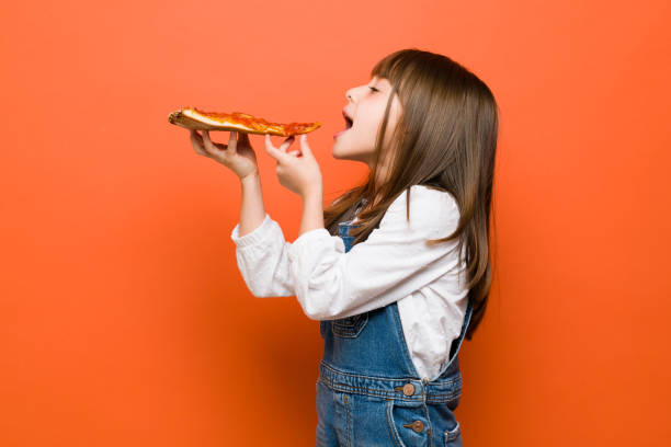 Little girl enjoying a slice of pizza stock photo