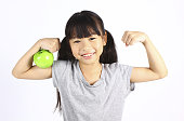 小さな女の子はリンゴを披露しながら彼女の筋肉を曲げる
