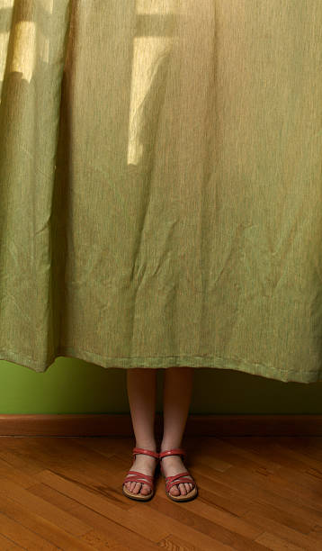 little girl hid behind the curtain stock photo