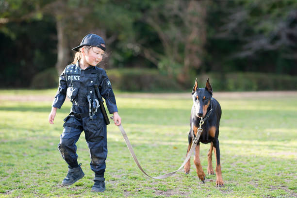 警察衣装とドー ベルマンの相棒の少女 - 動物飼育管理　日本 ストックフォトと画像