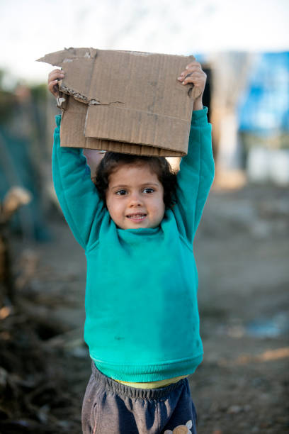 little girl in refugee camp showing paper stock photo