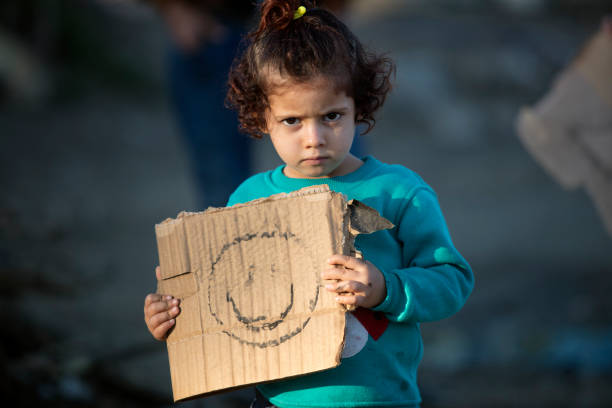 little girl in refugee camp showing paper with smiley stock photo
