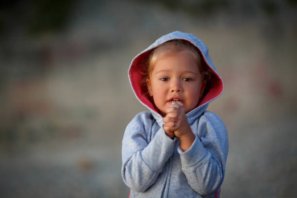 Little girl is standing with her hands clasped and begging to fulfill her desire  prayer request stock pictures, royalty-free photos & images