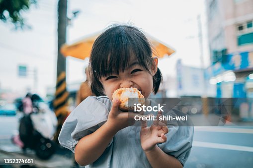 istock Little girl is very happy to eat cream puffs 1352374651