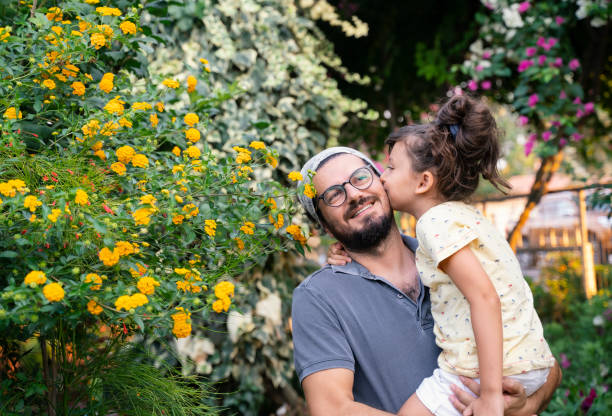 Little girl kissing his father at backyard stock photo