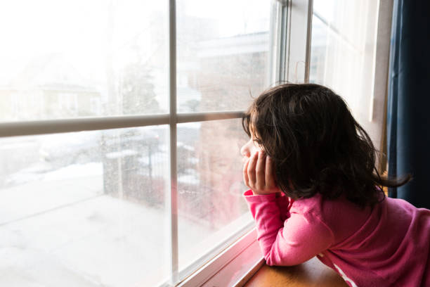 little girl looking out the window stock photo