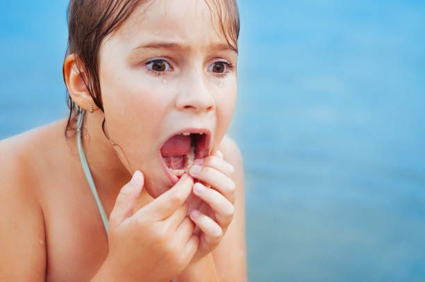 Little girl loses milk tooth in summer A little girl loses a baby tooth while swimming and relaxing on the beach, frightened rotten teeth in children stock pictures, royalty-free photos & images