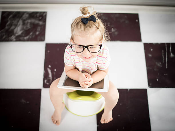 Little girl on a potty with tablet PC stock photo