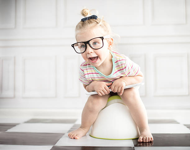 Little girl on white potty with digital tablet stock photo