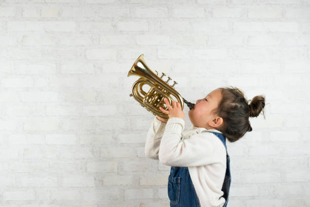 Little girl playing the trumpet Little girl is playing a small trumpet wind instrument stock pictures, royalty-free photos & images