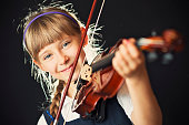 Closeup of little girl playing a violin. Fine noise applied. Shallow depth of field.