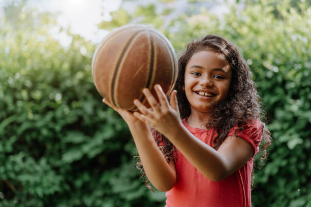 Little girl playing with basketball in the yard stock photo