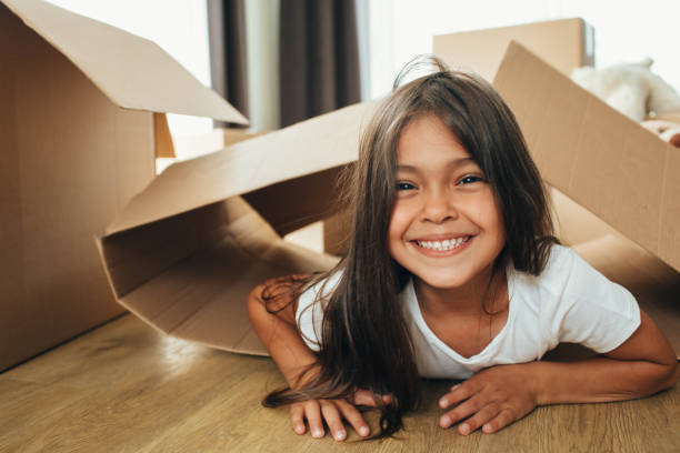 маленькая девочка играет с картонной коробкой, в свой новый дом. - kids playing стоковые фото и изображения