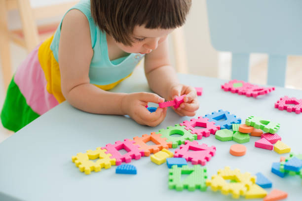 little girl playing with puzzle, early education stock photo