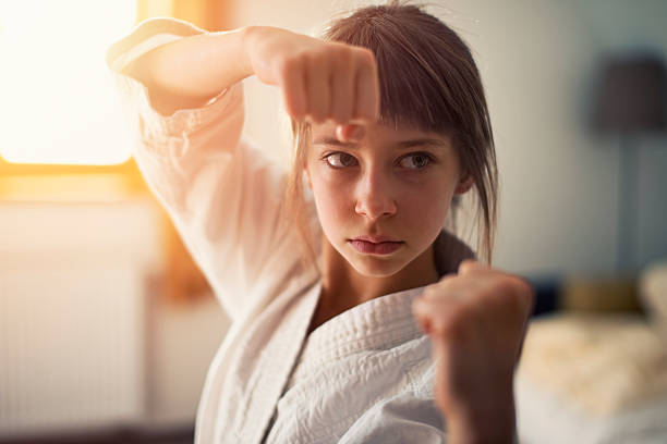 Little girl practicing karate Closeup portrait of little girl aged 10 practicing karate in her room. The girl is lit by sunlight from the window. warrior person stock pictures, royalty-free photos & images