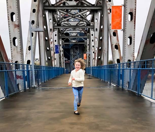 A little girl runs carefree on a bridge in Little Rock, Arkansas A little girl runs carefree on the Junction  Bridge in Little Rock, Arkansas michael dean shelton stock pictures, royalty-free photos & images