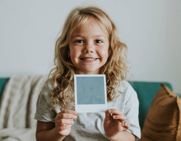 Little girl showing a photo from an instant camera Little girl showing a photo from an instant camera holding photos stock pictures, royalty-free photos & images