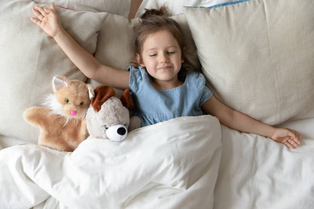niña durmiendo en la cama con juguetes de animales esponjosos - mattresses for children  fotografías e imágenes de stock