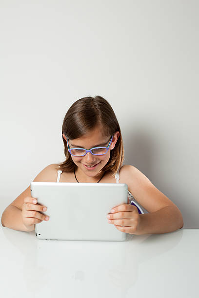 Little Girl Smiling in front of her Tablet PC stock photo
