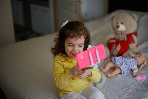 Little girl taking a selfie with her new toy mobile camera stock photo