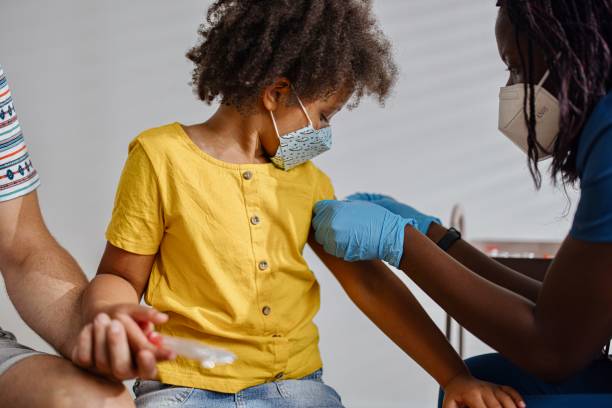 Little girl taking a vaccine from her doctor, pediatrist stock photo