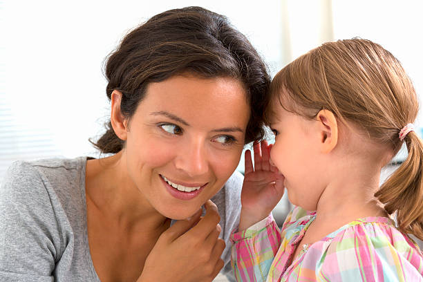 Little girl telling her mother secret stock photo