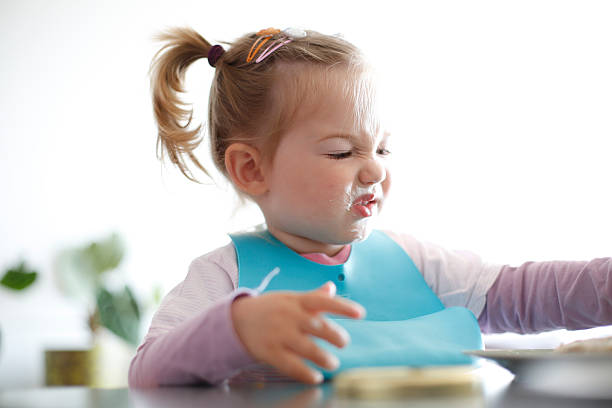 Little girl toddler picking her food, making faces Little girl toddler picking her food, making faces. Childhood problems, picky eater, eating habits, terrible two concept. complaining stock pictures, royalty-free photos & images