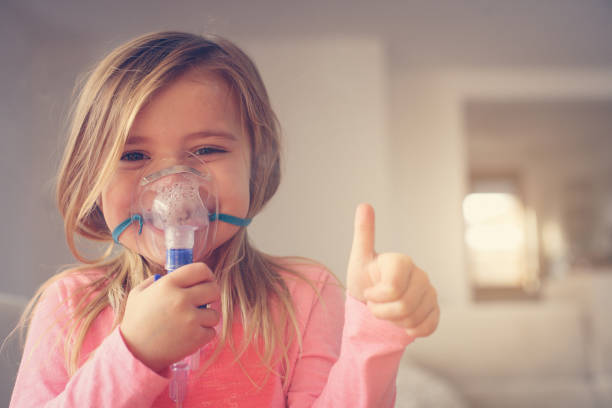 Little girl using inhaler. stock photo