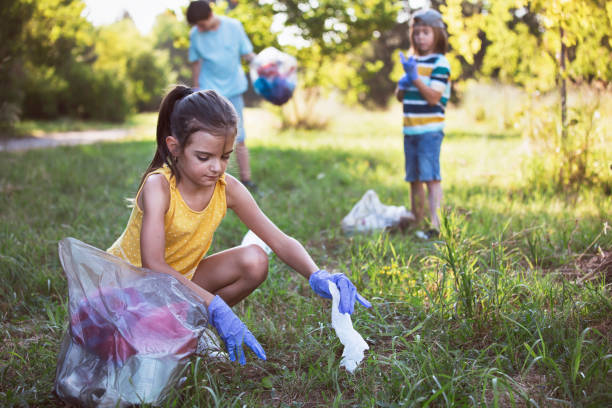 Little girl, volunteer picking up trash in the park stock photo