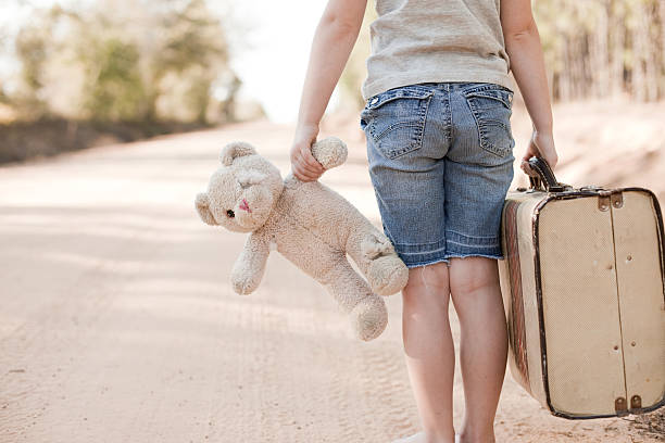 Little Girl Walking with Old Teddy Bear and Suitcase stock photo