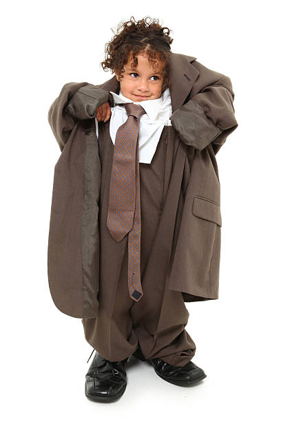 Little girl wearing grown up man's business suit Adorable 3 year old mixed race girl in over-sized baggy suit over white background. oversized object stock pictures, royalty-free photos & images