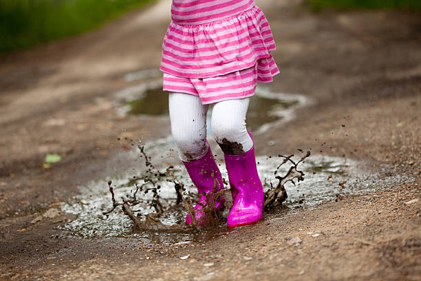 Little girl wearing pink jumping in a puddle stock photo