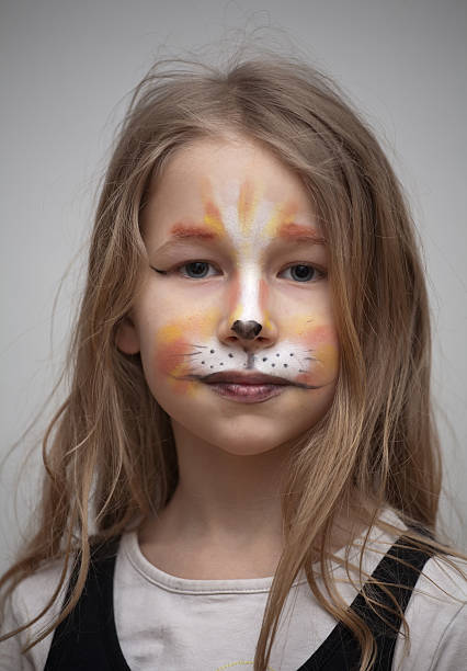closeup portrait of little girl with cat painting makeup on the face...