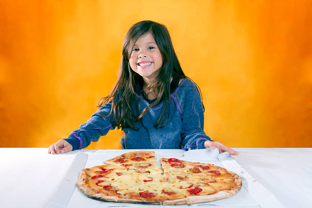 Little girl with cheerful expression in front of his pizza stock photo
