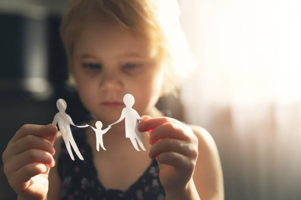 little girl with paper family in hands. concept of divorce, custody and child abuse little girl with paper family in hands. concept of divorce, custody and child abuse divorce stock pictures, royalty-free photos & images