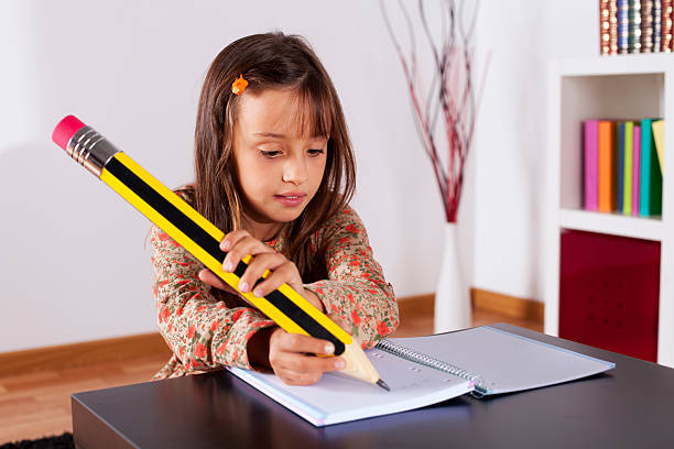Little girl writing with a giant pencil stock photo
