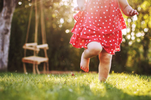 어린 소녀의 맨발은 잔디에. 석양에 흐르는 어린 소녀 - 맨발 뉴스 사진 이미지