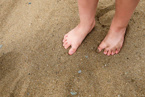A little girl's / child's feet in the sand on a beach A little girl's / child's feet in the sand on a beach. Blank empty copy space for text. human feet buried in sand. summer beach stock pictures, royalty-free photos & images