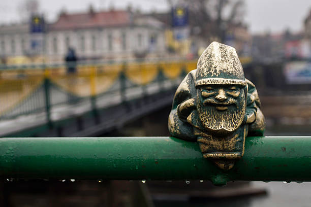 Little gnome statue on the bridge in the rain Little wet garden gnome figurine sitting on a green fence on the bridge in the rain wroclaw stock pictures, royalty-free photos & images