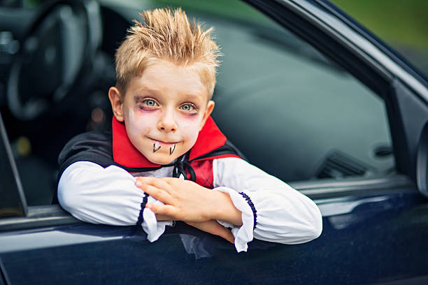 Little halloween boy smiling out of the car Portrait of a little boy on halloween dressed up as a vampire. The boy is aged 6 and is smiling from the car window. period costume stock pictures, royalty-free photos & images