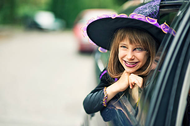 Little halloween witch smiling out of the car Portrait of a little girl during halloween dressed up as a witch. The girl is aged 9 and is smiling from the car window. Street visible in the background and a lot of nice copy space. period costume stock pictures, royalty-free photos & images