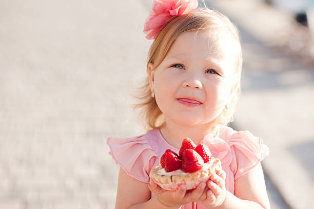 Little kid girl eating cake stock photo