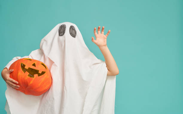 little kid in ghost costume Happy Halloween! Cute little kid in ghost costume on teal background. costume stock pictures, royalty-free photos & images
