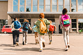 小さな子供の小学生は、スクールバスへの授業のために学校の建物に急いで走っている生徒を生徒にしています。学校へようこそ。新学期の始まり