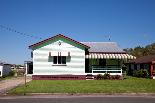 Tidy little old style house with clear blue sky and green grass and overhead power line connected to it – Queensland Australia. Click to see more...